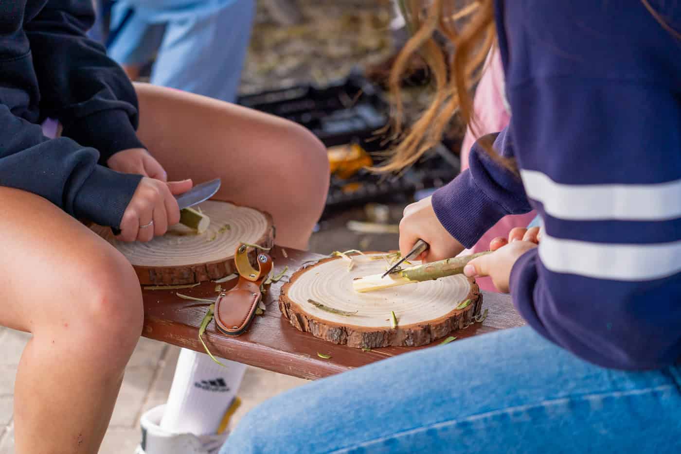 Kinder schneiden Holz für das Lagerfeuer bei Angeboten in Zingst.
